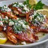 Tender marinated Greek Chicken with Lemon and Feta plated on a bed of rice, topped with crumbled feta and fresh herbs.