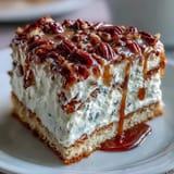 Decadent Butter Pecan Tres Leches Cake slice on a white plate, topped with toasted pecans and a dollop of whipped cream.