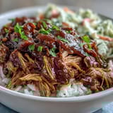 Golden pulled pork bowl with fluffy white rice, tangy coleslaw, and a drizzle of smoky BBQ sauce.