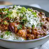 A steaming bowl of rich chili with vibrant beans, peppers, and a dollop of sour cream.  