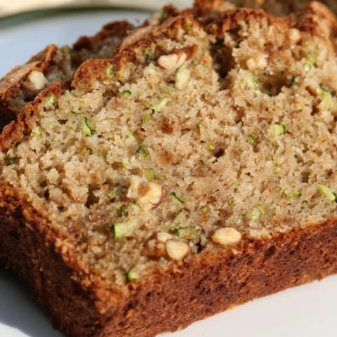 Moist Zucchini Bread loaf with warm cinnamon aroma, slices fanned out on a rustic plate for breakfast.