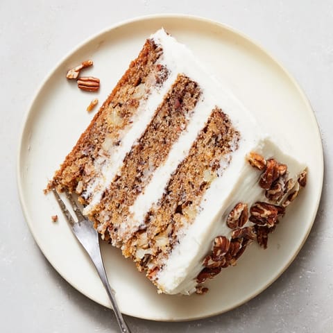 Freshly baked Hummingbird Cake slices reveal moist layers with banana, pineapple, and toasted pecan garnish.