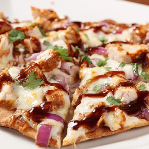 Sizzling BBQ chicken flatbread on a rustic wooden board, featuring tangy sauce, gooey cheese, and fresh cilantro garnish for a flavorful meal.