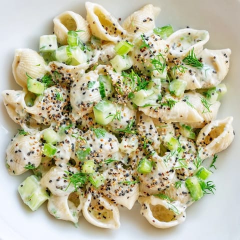 Cucumber Crunch Pasta Salad in a white serving bowl, featuring a creamy tangy dressing, green onions, and everything bagel seasoning for added texture.