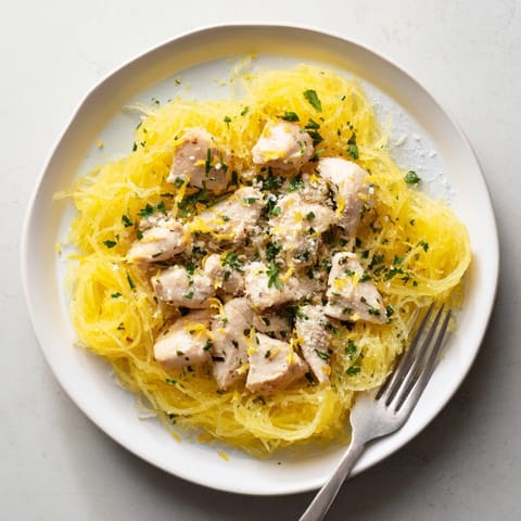 A close-up view of Lemon Garlic Chicken Spaghetti Squash, featuring savory chicken and bright yellow lemon zest over fluffy squash.