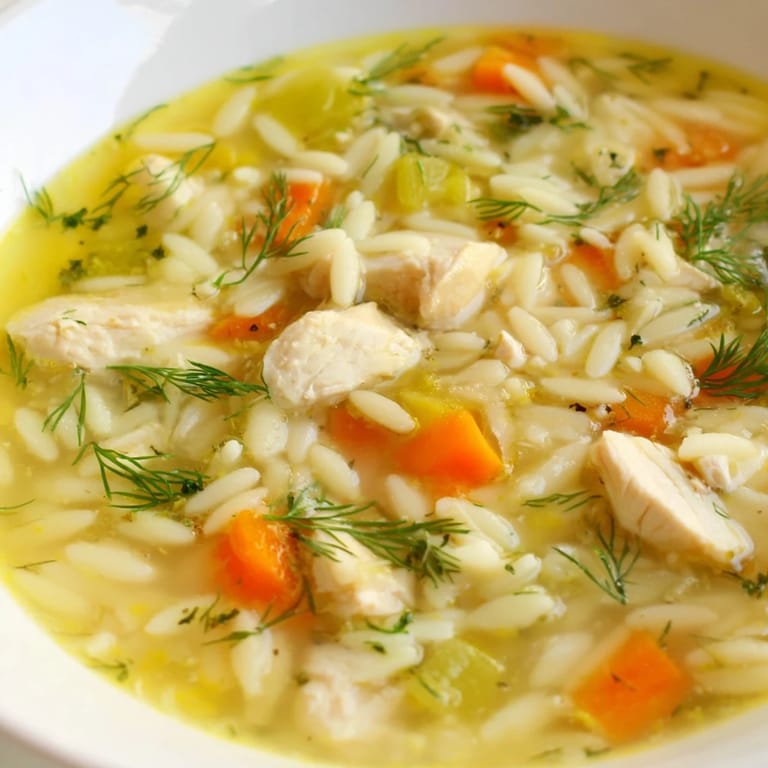 Homemade Chicken Lemon Orzo Soup simmering in a pot, featuring bright lemon zest, carrots, celery, and shredded chicken.