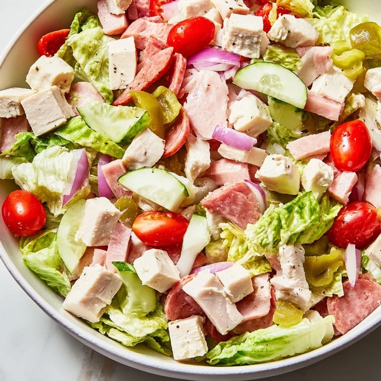 Vibrant Italian Deli Chopped Chicken Salad served in a rustic bowl, showcasing chopped chicken, salami, and cheese alongside bright tomatoes and cucumbers for a refreshing, protein-packed meal.