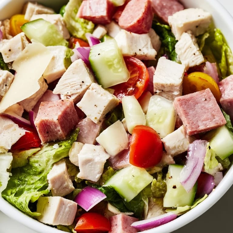 Hearty Italian Deli Chopped Chicken Salad tossed with crunchy vegetables, savory salami, and provolone, drizzled in a tangy red wine vinaigrette and garnished with fresh pepperoncini.