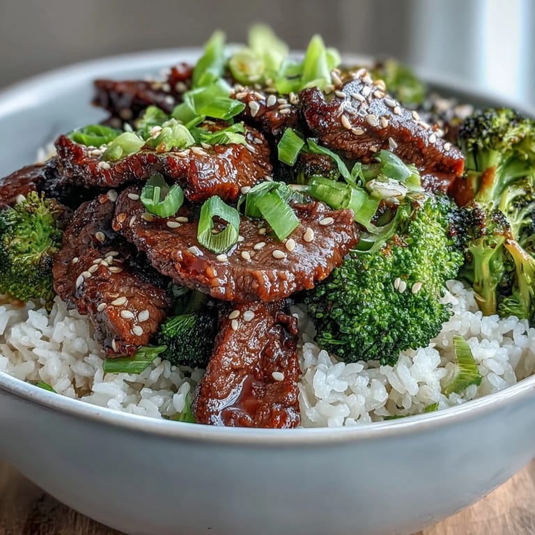 Close-up of sizzling Beef and Broccoli Bowl with tender beef strips, crisp steamed broccoli, and glossy sauce tossed together.