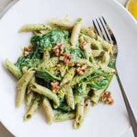 A bowl of Creamy Spinach Walnut Pasta garnished with toasted walnuts and lemon zest, perfect for a quick vegan weeknight dinner.  