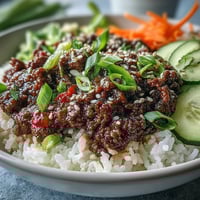 A close-up of a Korean Ground Beef Bowl with savory beef, fluffy rice, and tangy pickled carrots and cucumbers.