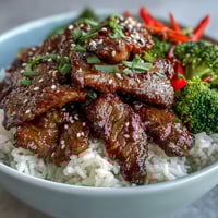 Fluffy rice topped with tender teriyaki beef, crisp broccoli, and carrots, garnished with green onions and sesame seeds.
